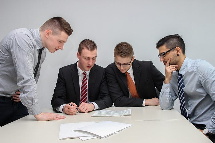 Four businessmen looking at papers in a boardroom. Four businessmen looking at papers in a boardroom.