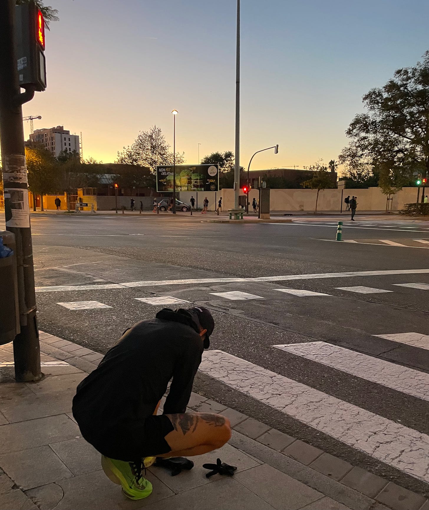 The author kneeling at a traffic light fixing his shoe laces on the roads of Valencia