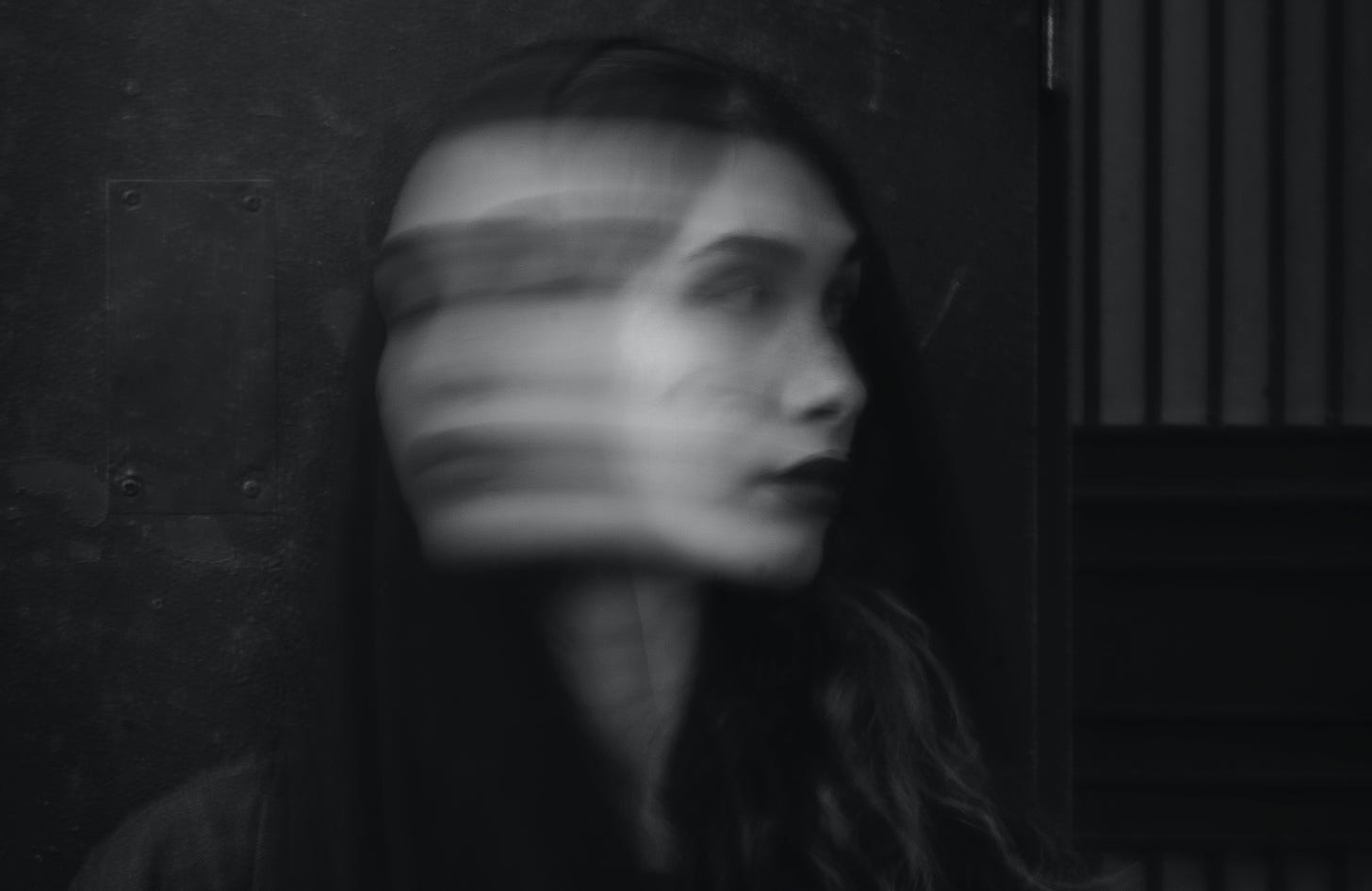 A black and white photo of a woman, her face blurred and indistinct from quick movement.