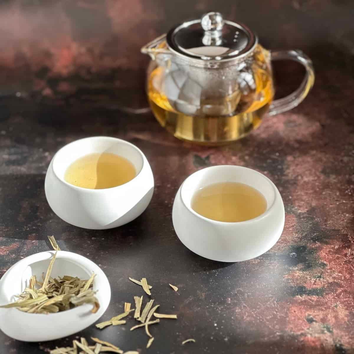 sea buckthorn brewed tea in teapot and cups with dried tea on the side