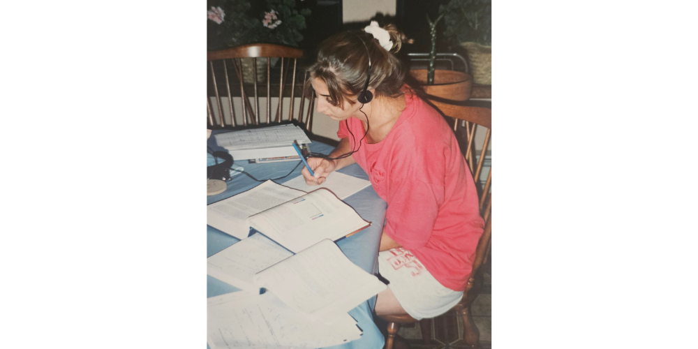 A picture of me somewhere around the age of 19, sitting at a table taking notes from three open textbooks. 