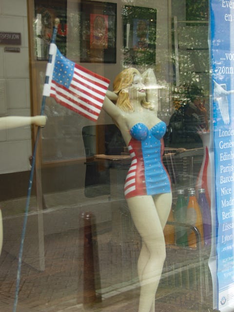 A mannequin in a swimsuit holding a flag

Description automatically generated