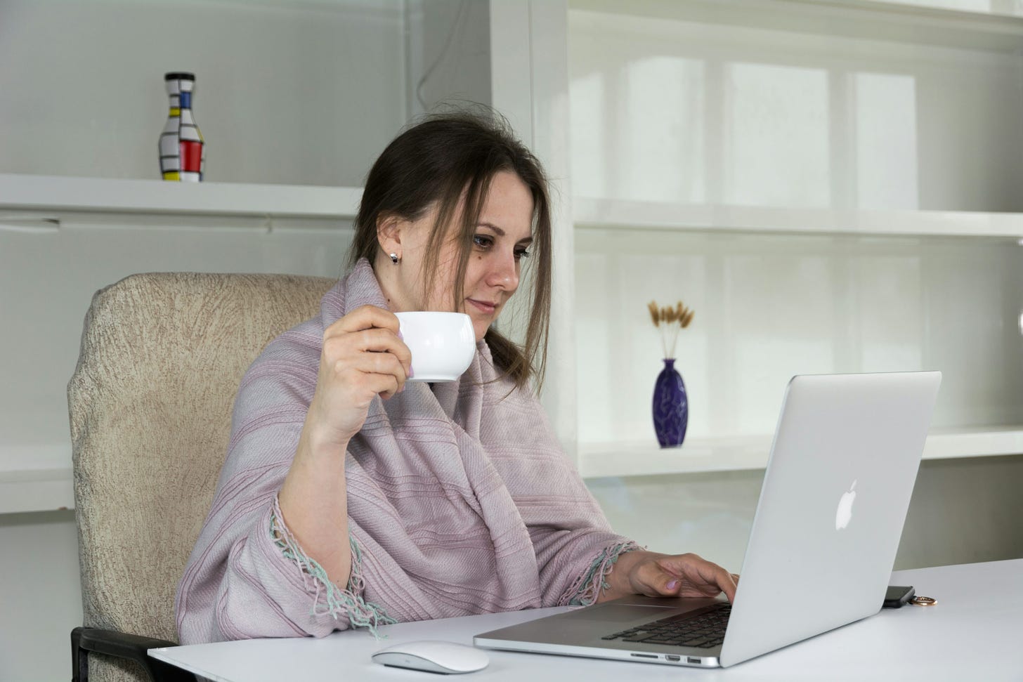 特色图片：a woman sitting at a desk with a laptop and a cup of coffee