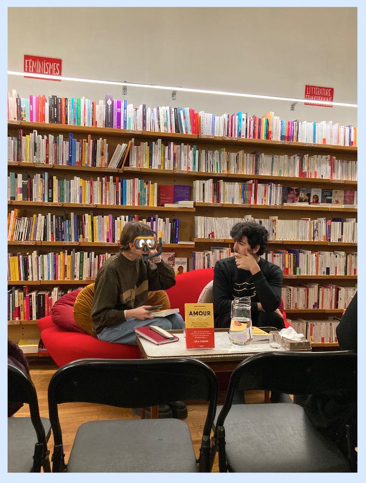 Jamal Ouzzani est assi avec la·le libraire sur un canapé rouge devant un rayon de livre pour la rencontre