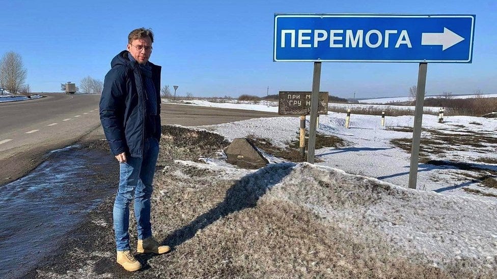 lya Barabanov next to a road sign to the town of Peremoha, which in Ukrainian means victory. ©Ilya Barabanov/BBC