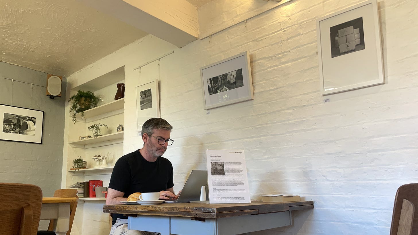 Man at a computer in a cafe under balck and white photographs on the wall