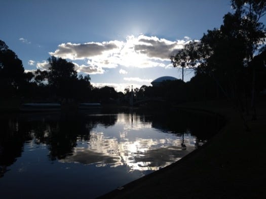 Bright sun shining through clouds, reflected on the Torrens river