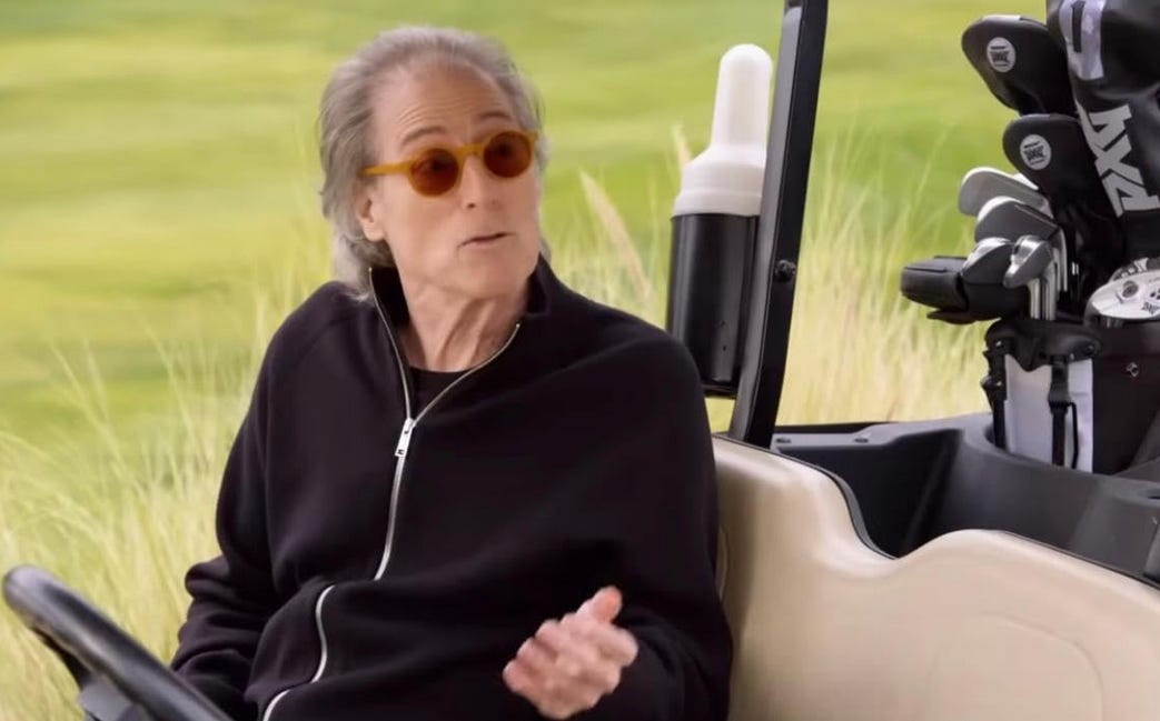 Richard Lewis in Season 12 episode 3 of Curb Your Enthusiasm; he is sitting in a golf cart facing the camera while speaking and gesturing