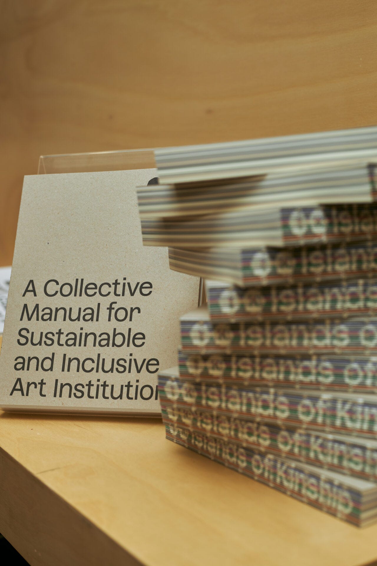 A stack of books, maybe for sale, called A Collective Manual for Sustainable and Inclusive Art Institutions.