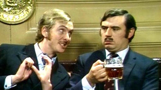 Screen shot of Eric Idle and Terry Jones of Monty Python. Idle is playing the "Nudge Nudge" character to a frustrated Jones.