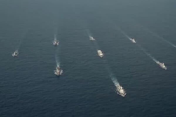 An aerial view of several military ships moving in formation.