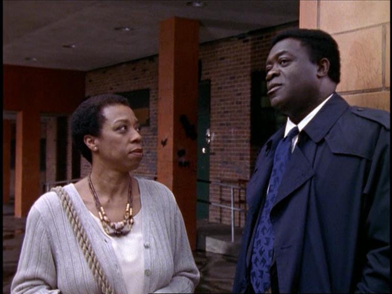 This still image from "Blood Ties (Part 3)," the third episode of Homicide: Life on the Street's sixth season, shows Regina Wilson (played by Lynne Thigpen, left) looking at Lieutenant Al "Gee" Giardello (played by Yaphet Kotto, right) as they discuss their shared past. This still image from "Blood Ties (Part 3)," the third episode of Homicide: Life on the Street's sixth season, shows Regina Wilson (played by Lynne Thigpen, left) looking at Lieutenant Al "Gee" Giardello (played by Yaphet Kotto, right) as they discuss their shared past.