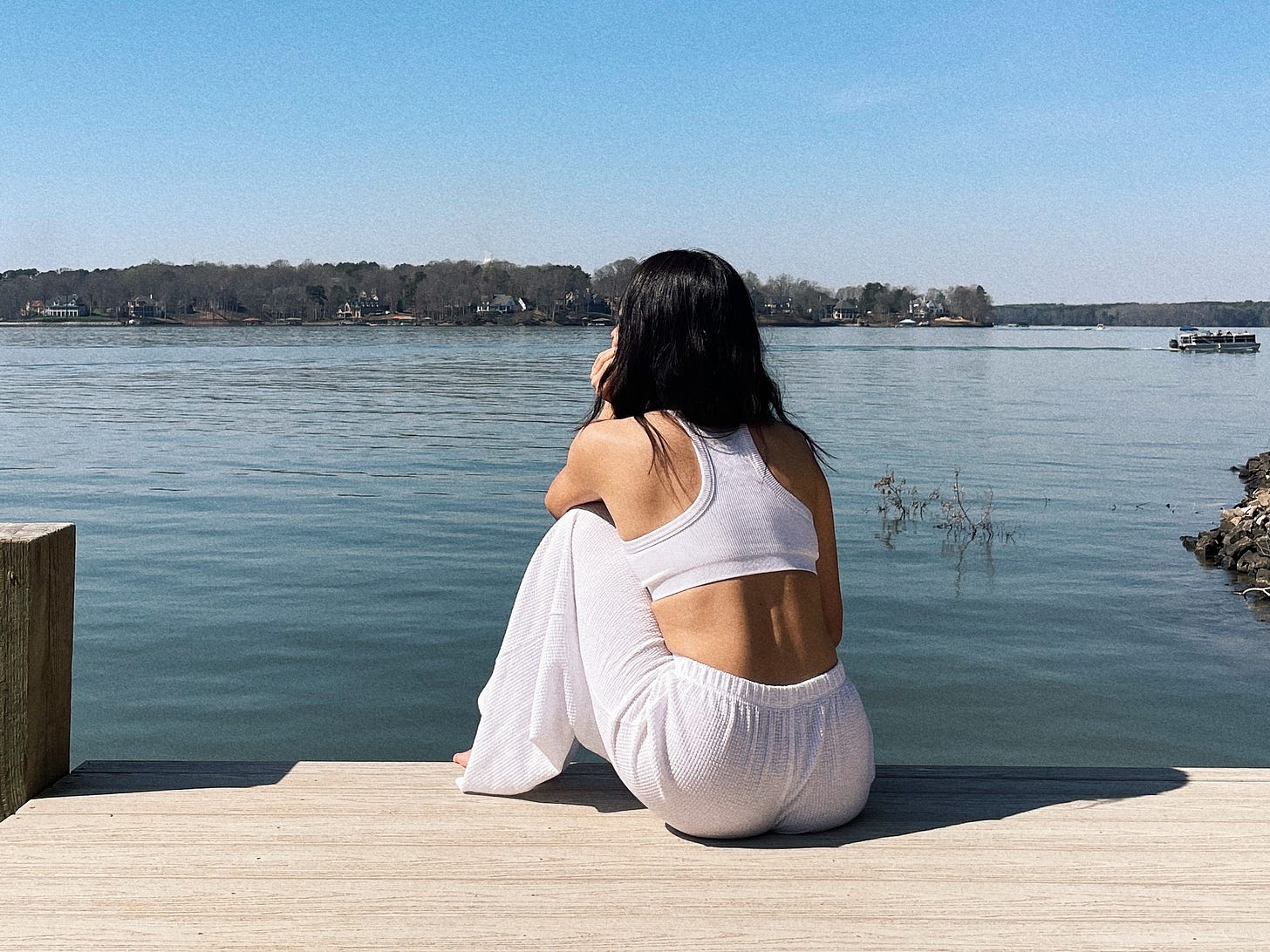 Woman sat on dock looking out over a lake