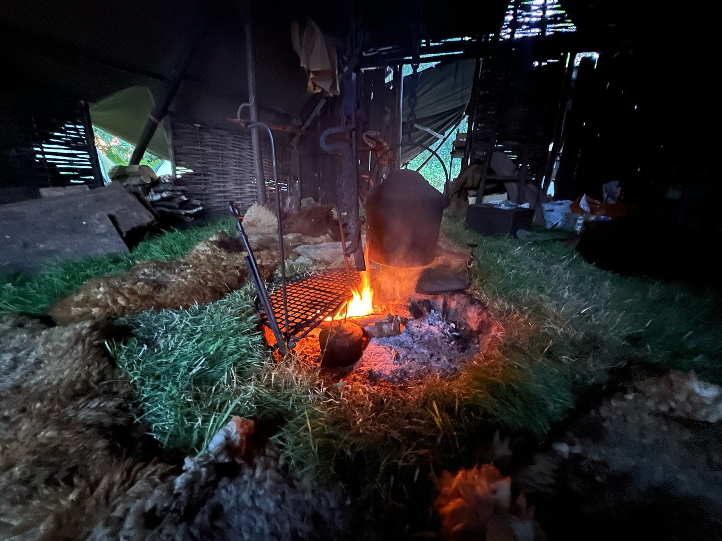 open fire with cooking pot, inside a wovenr hut