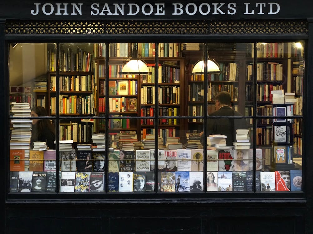Free A cozy London bookstore showcasing various books through a classic window display. Stock Photo