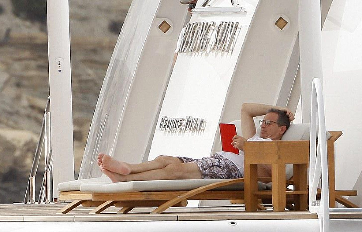 Bob reading a book lying on a deck chair on a boat