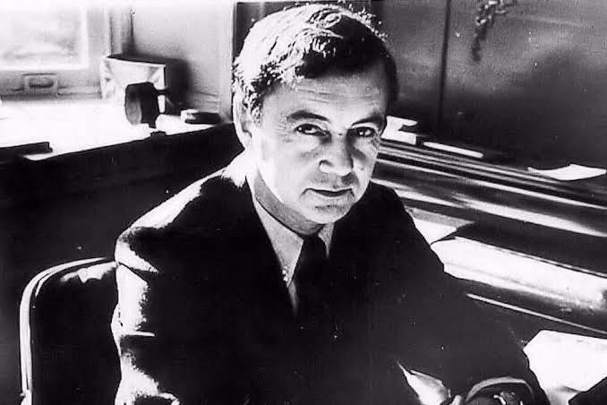 Black and white photo of sociologist Erving Goffman, looking sort of mischievious and maybe a little bit hot?