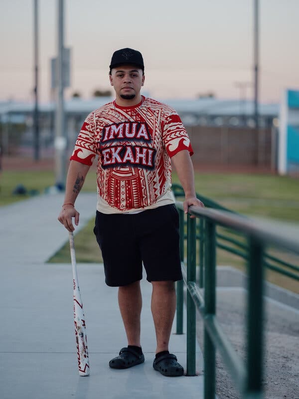 Devon Howard stands facing the camera and holding a white softball bat. 