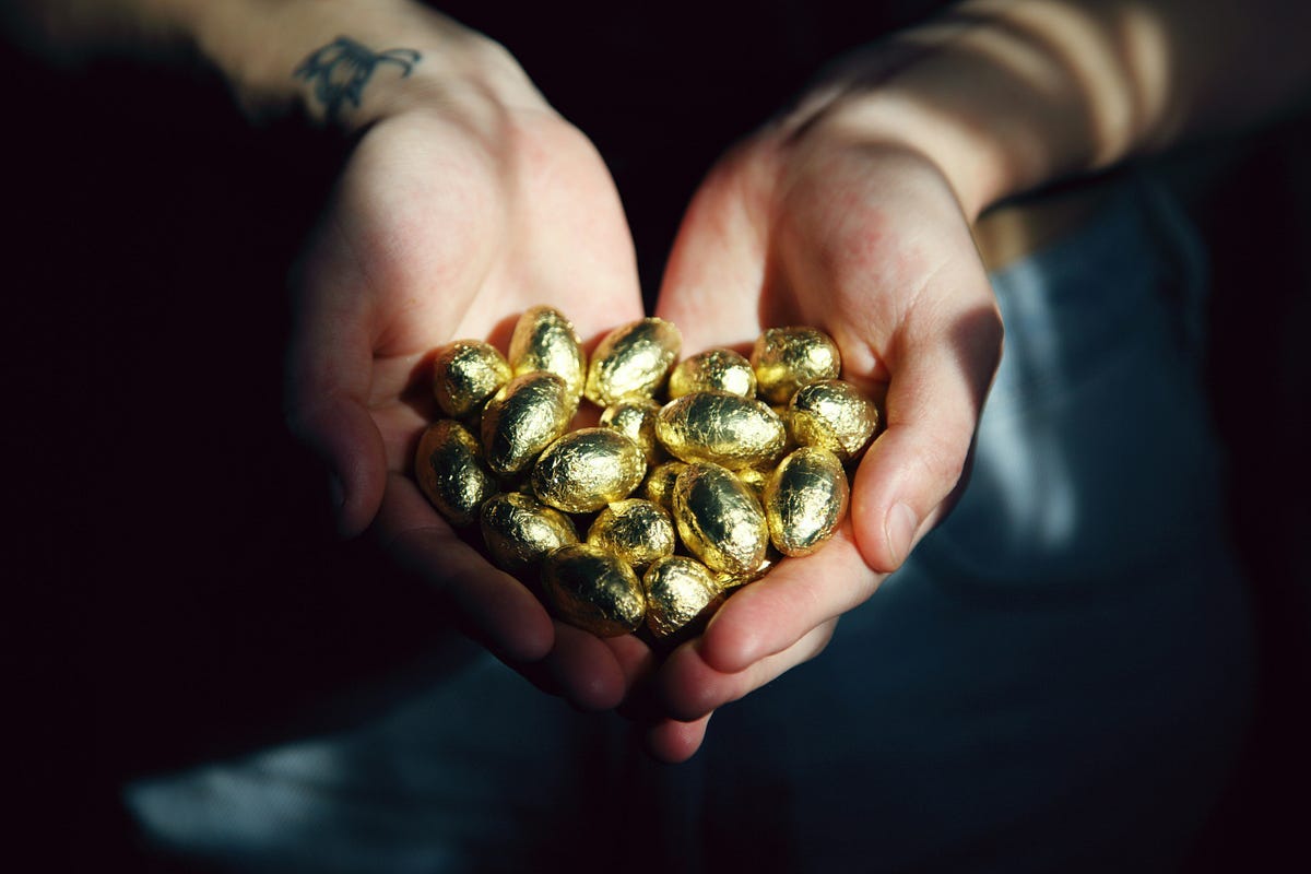 Person holding gold eggs in cupped hands. Person holding gold eggs in cupped hands.