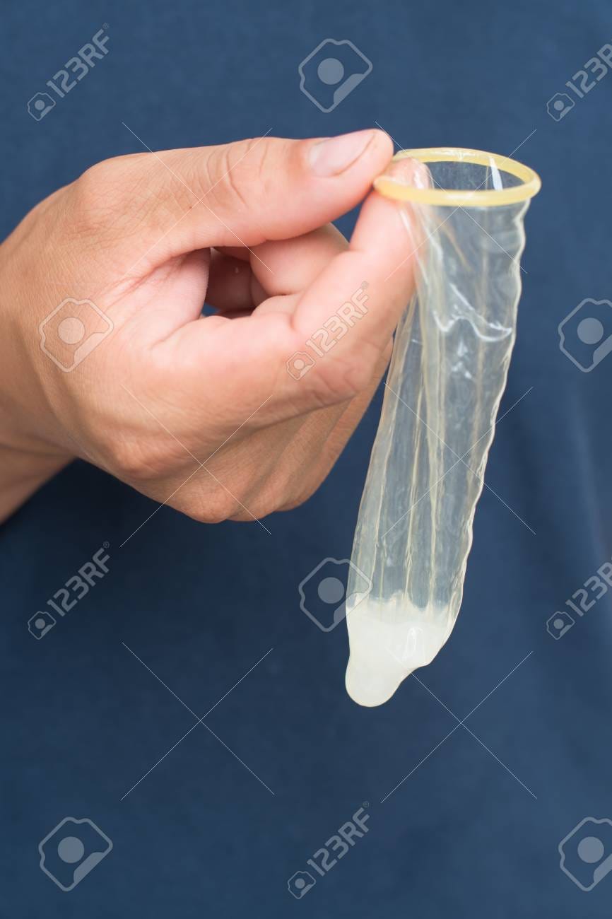 Used condom with semen holding in hand - 120702892