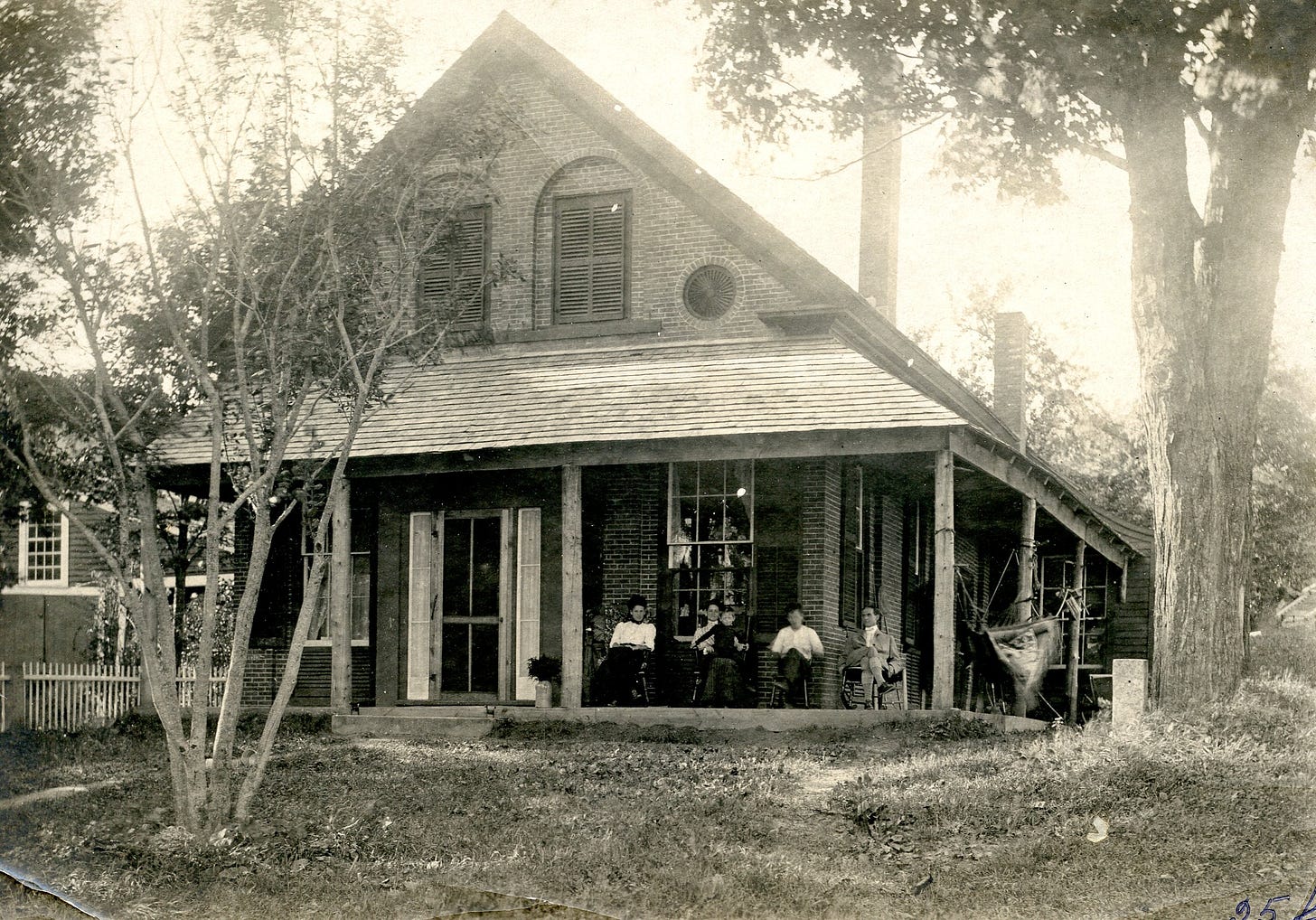 People on porch of brick house