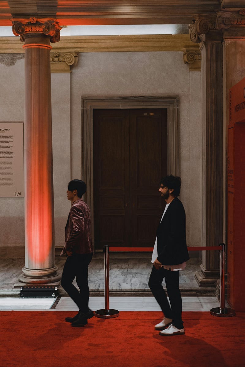 people walking way from each other on a red carpet