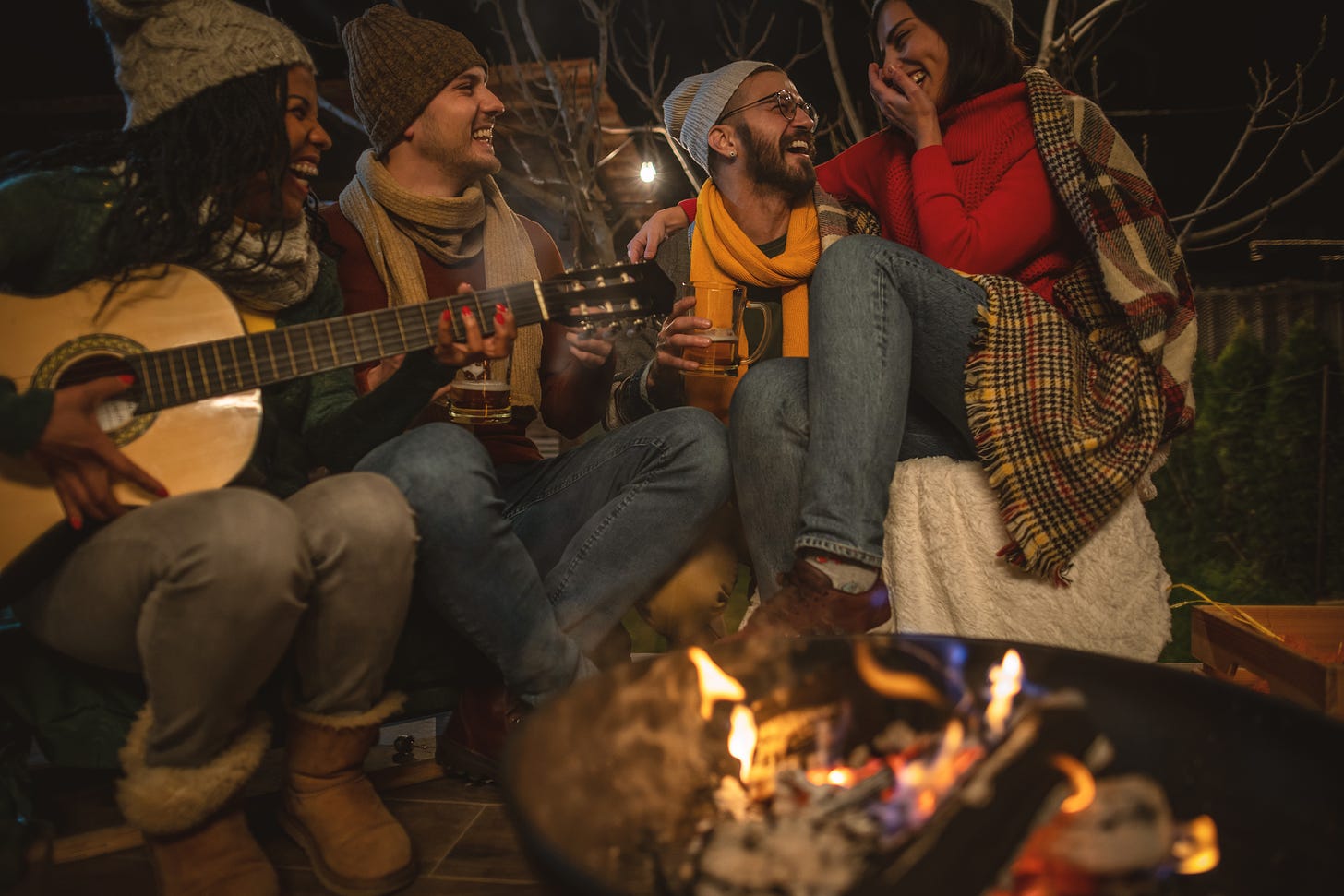 Happy young people sit around a campfire.