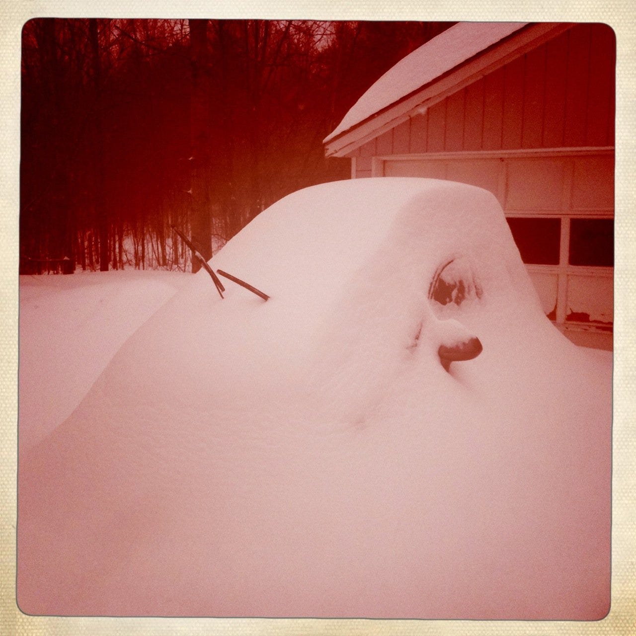 Image of a car almost completely buried in fresh snow.