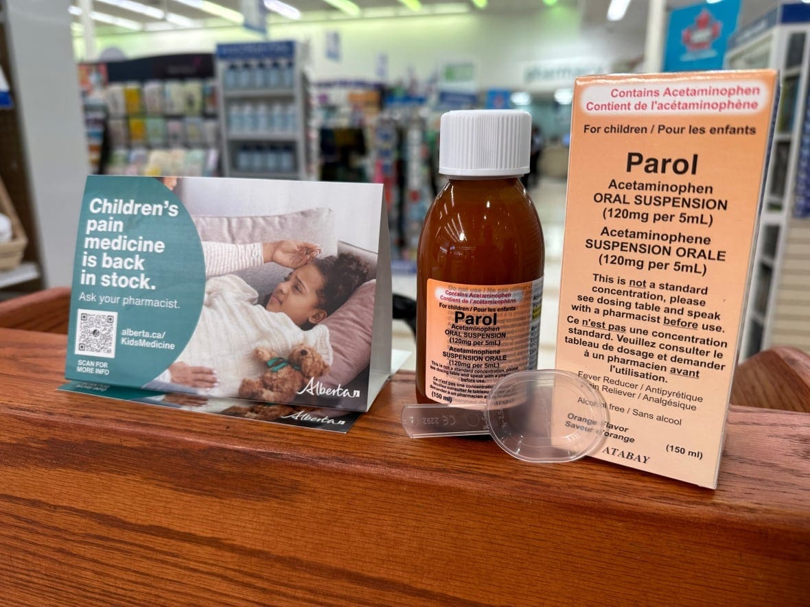 A medicine bottle, its box and a pamphlet on a wooden table.