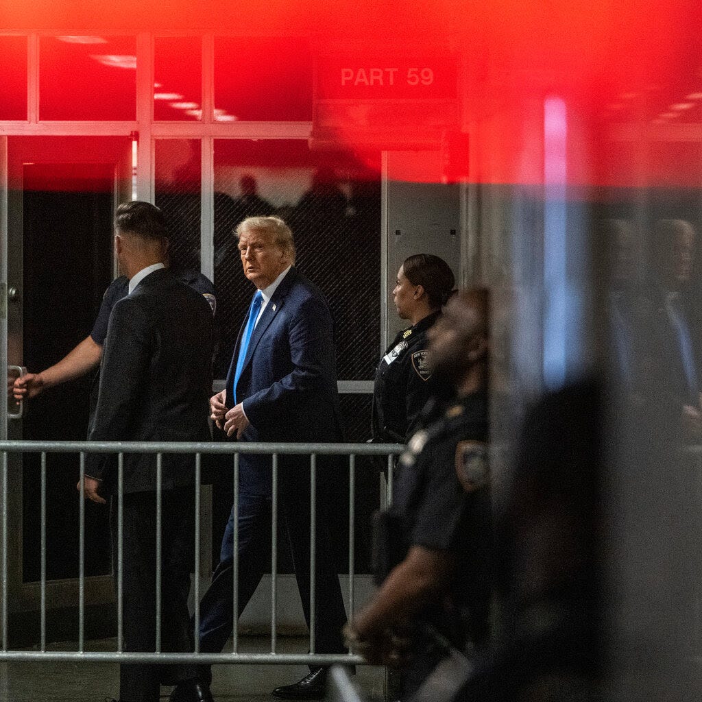 Donald Trump w towarzystwie funkcjonariuszy wychodzi z gmachu sądu.
