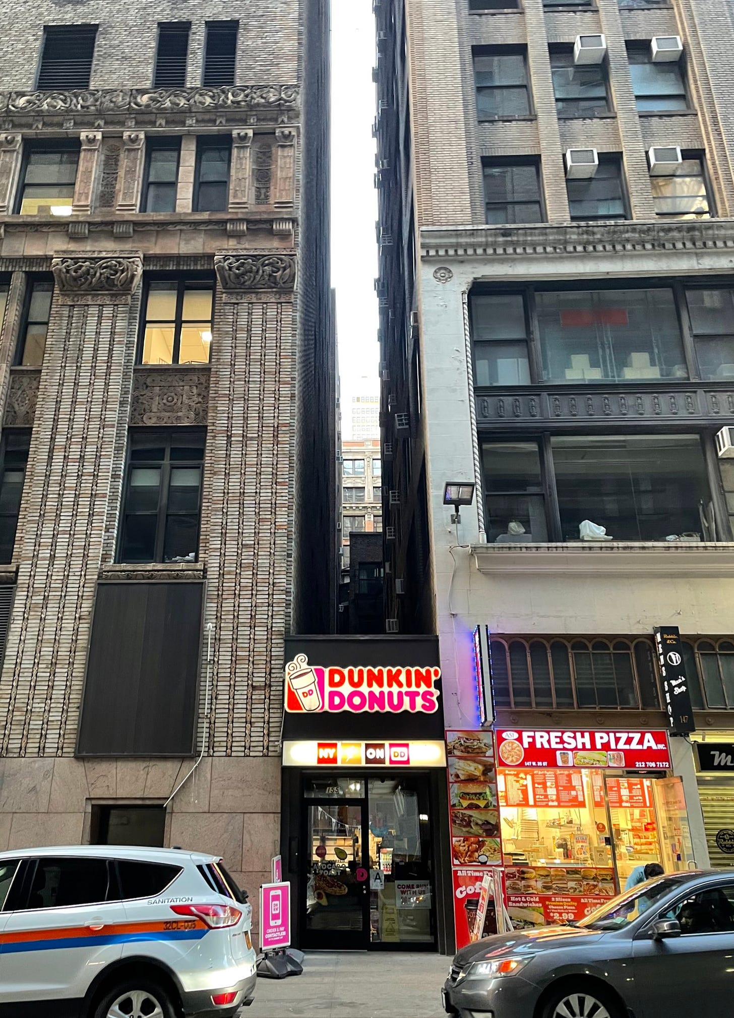 A dunkin donuts squeeze between two buildings