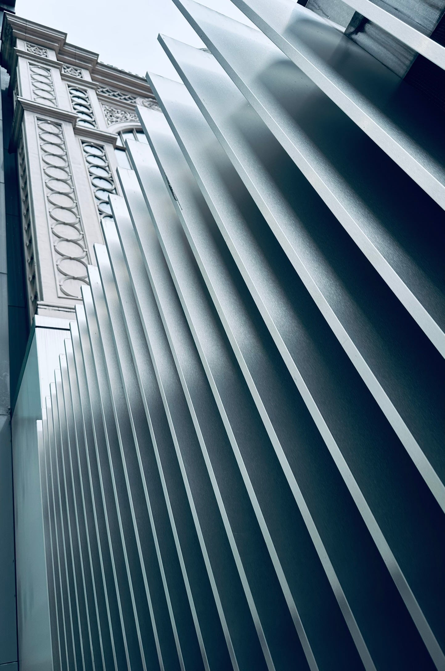 Close up of a metal fence with rigid edges, looking up and at angle on a grey winter day.