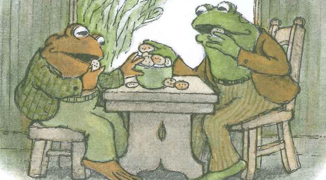 Illustration of Frog and Toad sitting at a table eating a big bowl of chocolate chip cookies together.