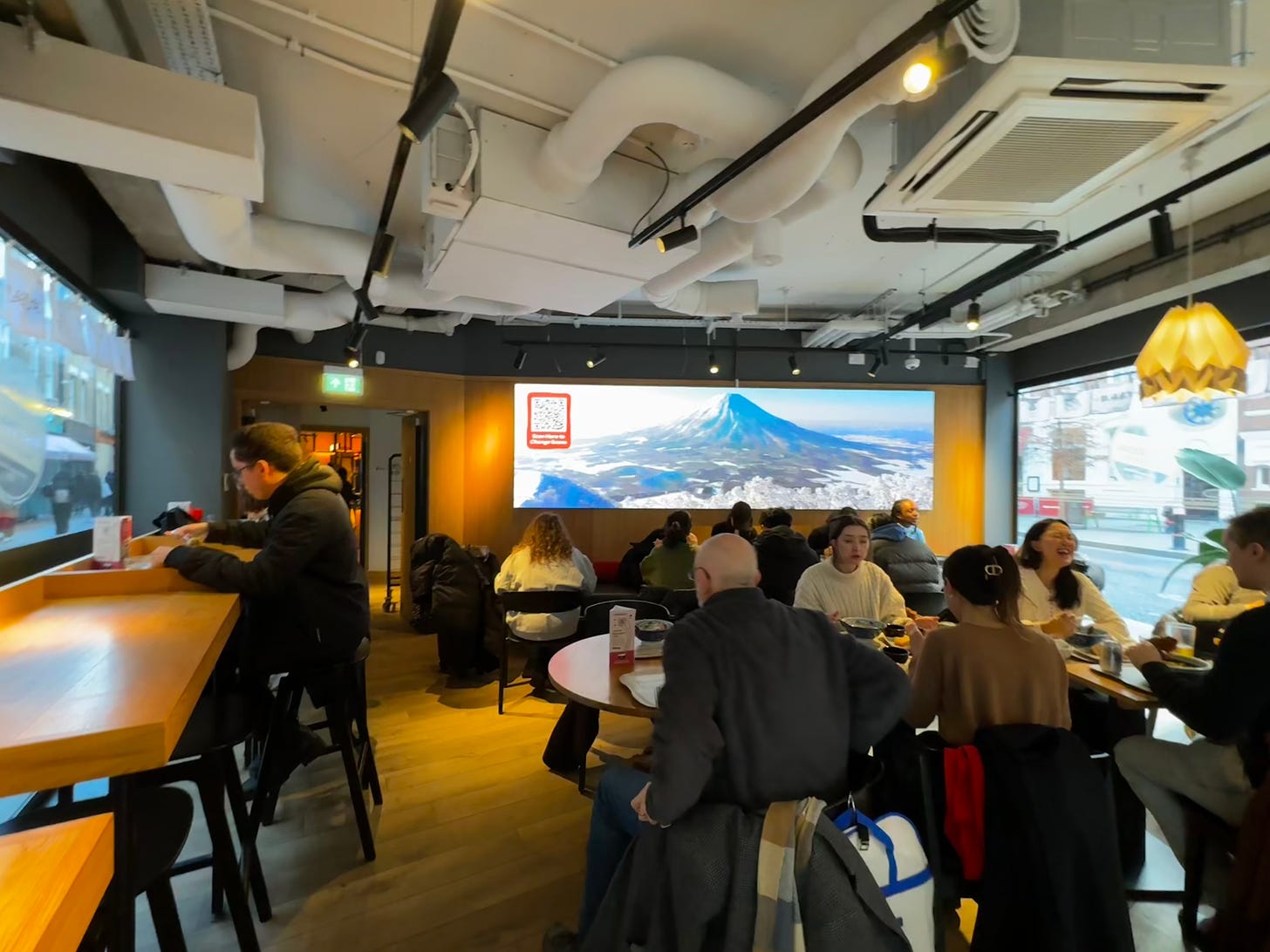 A restaurant with a big widescreen view of Mount Fuji on a wall