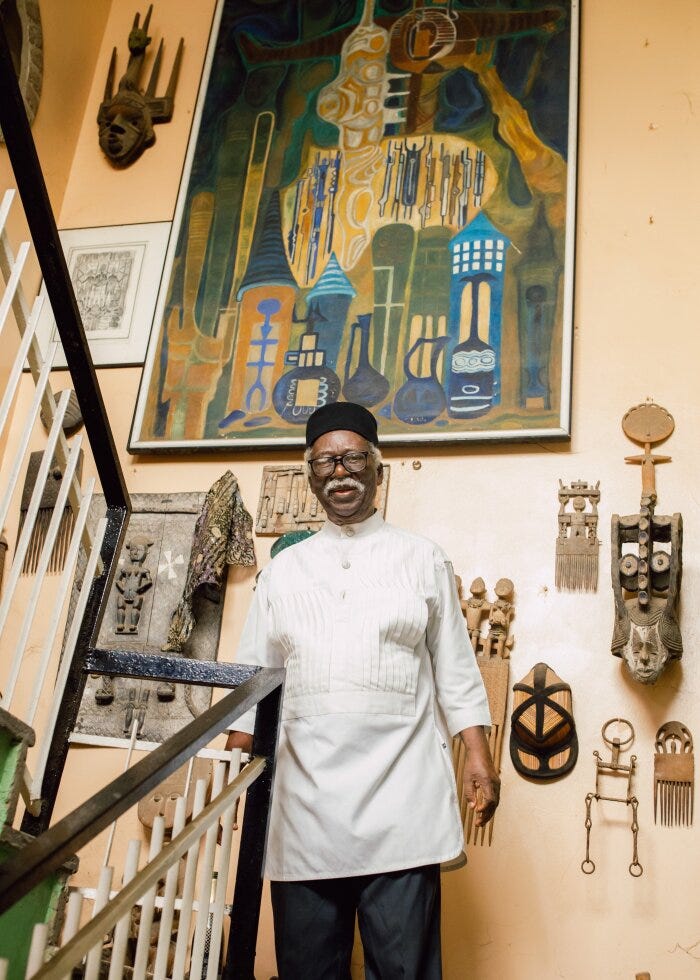 Artist Bruce Onobrakpeya stands before some of his art at his home studio in Lagos, Nigeria. The studio takes up two floors of his three-story house.