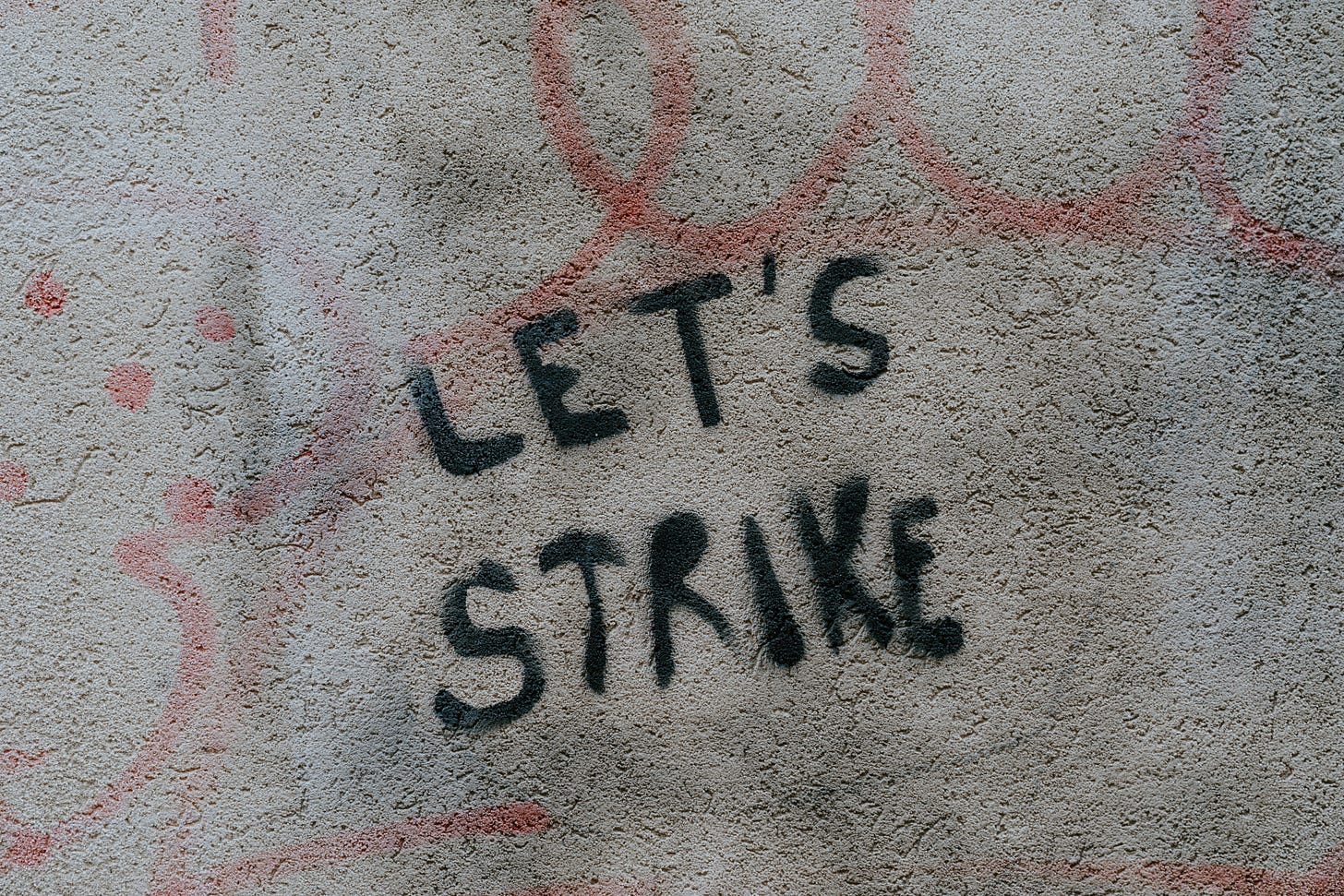 The words "Let's strike" are spraypainted in black on a great wall.