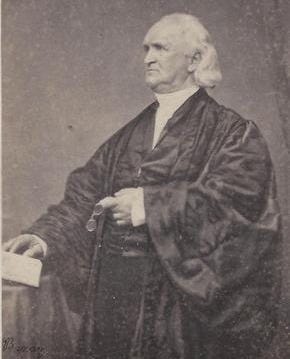 Older George B. Cheever sitting and wearing large, flowing black robe.