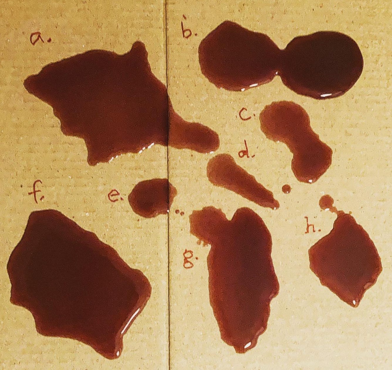 blobs of spilled wine on a piece of cardboard, each with a letter next to the blob, as if a diagram.