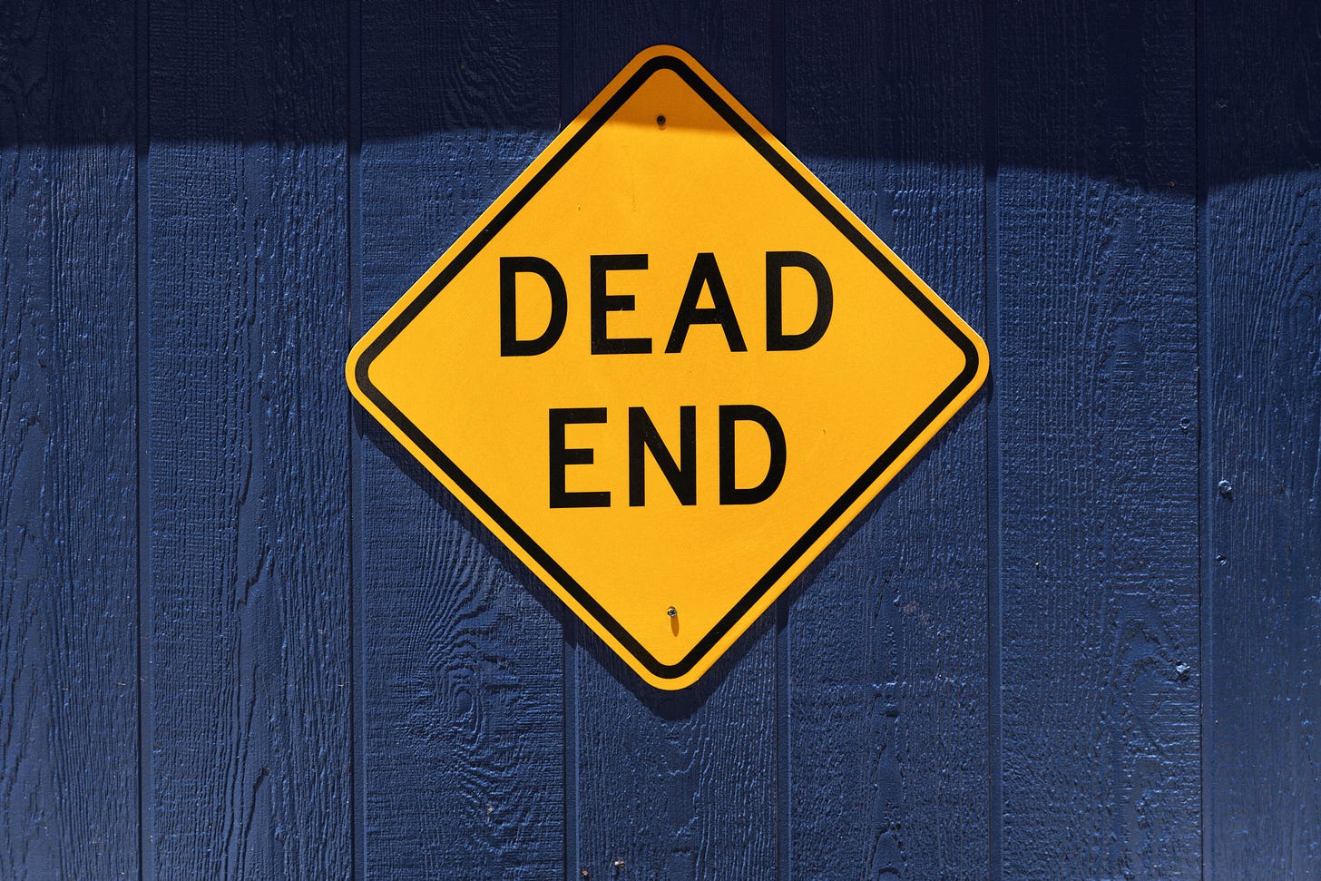 Cartello giallo a rombo con scritto "dead end" su sfondo blu