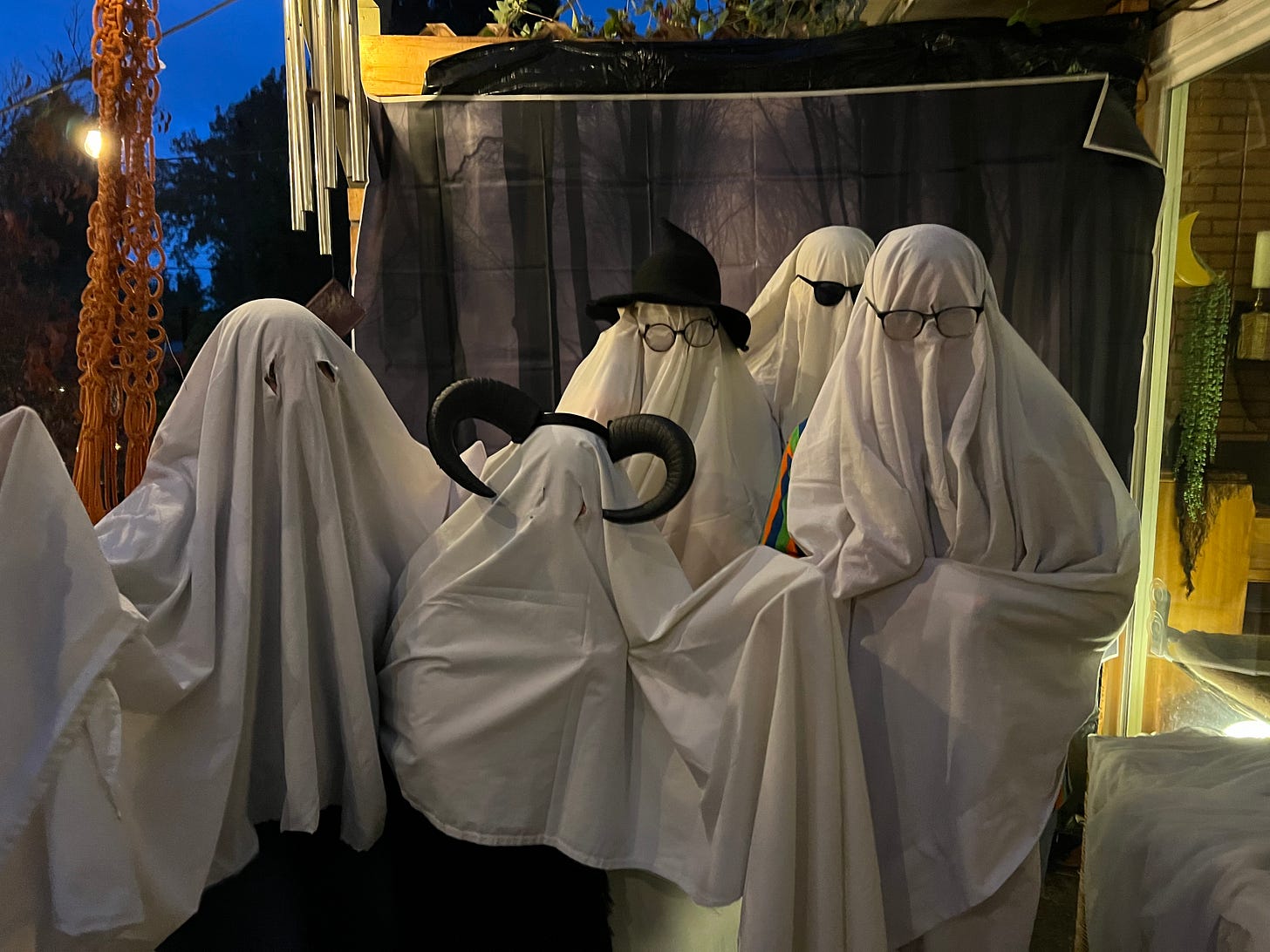 five adults wearing white sheets over them (to look like ghosts) are also sprouting horns and glasses