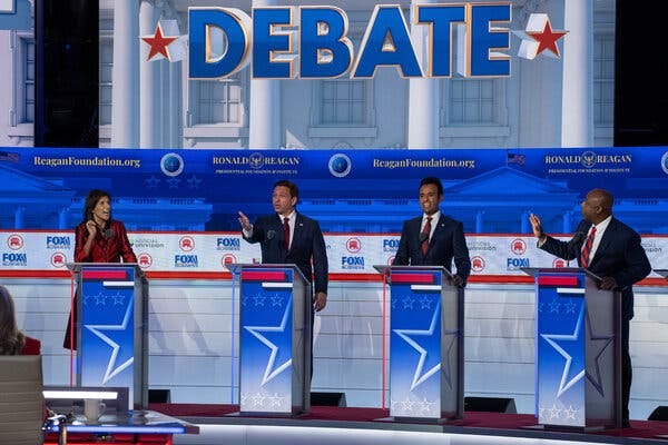 Several of the G.O.P. presidential candidates speak at the same time during the Republican debate while standing at red, white and blue podiums and gesturing with their hands.