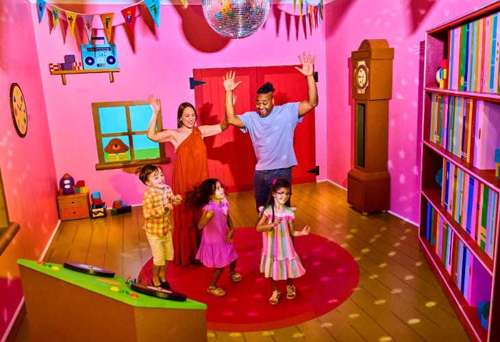 Children and adults dancing together in a colourful room