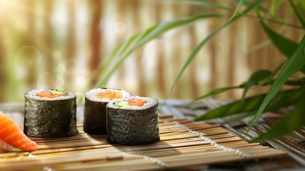 Colorful sushi clipart featuring different types of sushi rolls and garnishes on a wooden background.