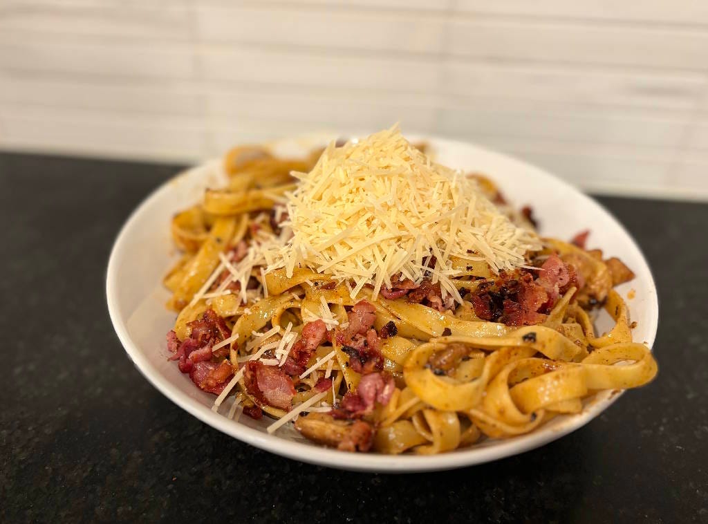 Pasta with bacon and chicken and cheese on a plate.