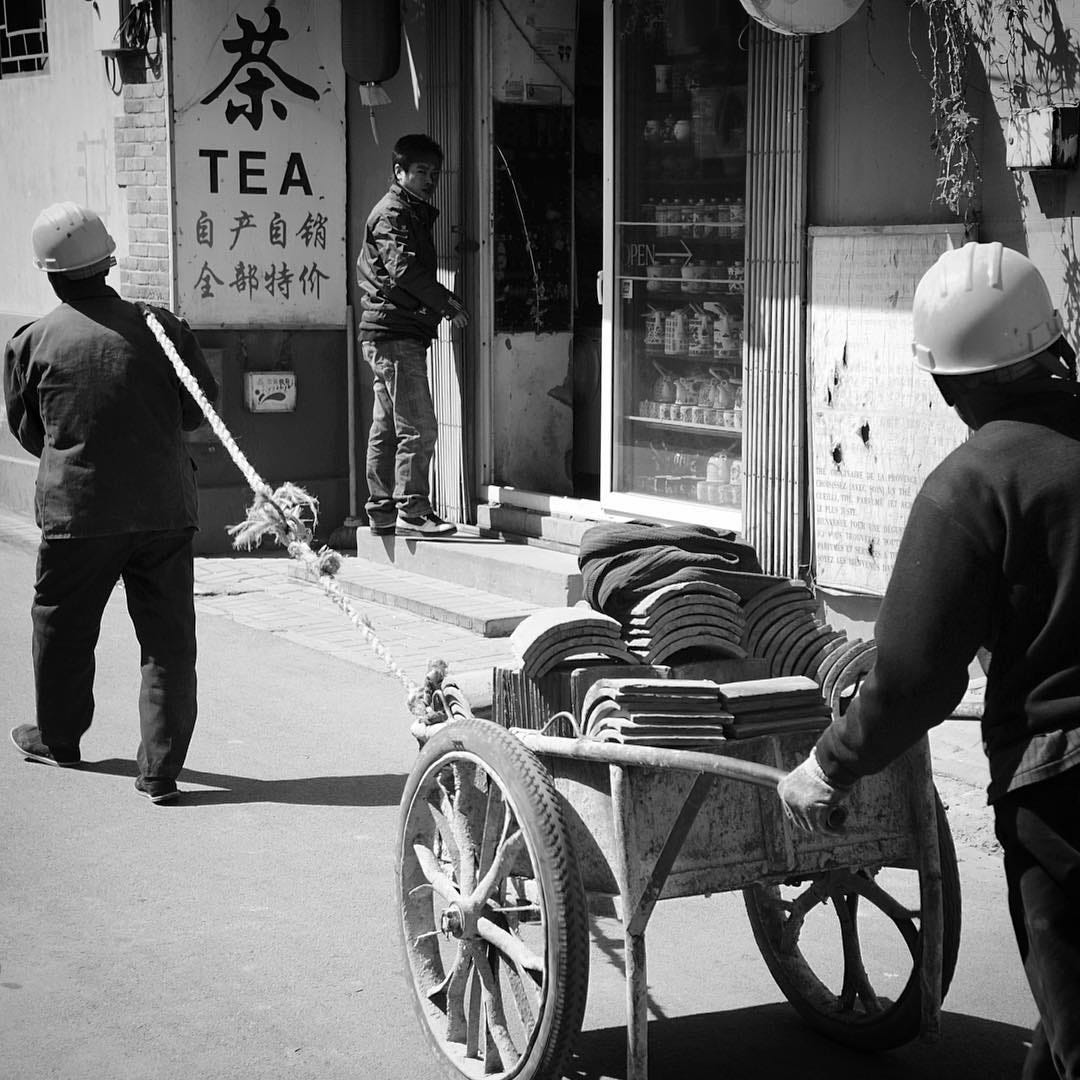 Migrant workers transporting roof tiles in a Beijing hutong.