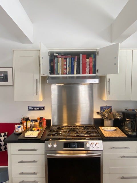 Bookshelf above a cooking stove. 