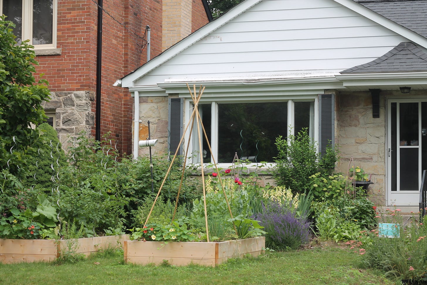 A bungalow with a garden and two raised veggie beds in front of it 