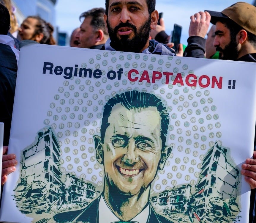 A man holds a poster reading "regime of captagon" 