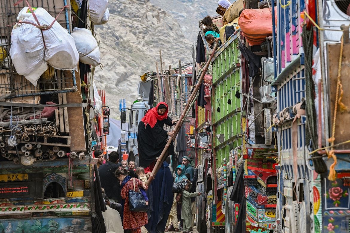 Afghan refugees climb a truck as they prepare to depart for Afghanistan, at a holding centre in Landi Kotal.