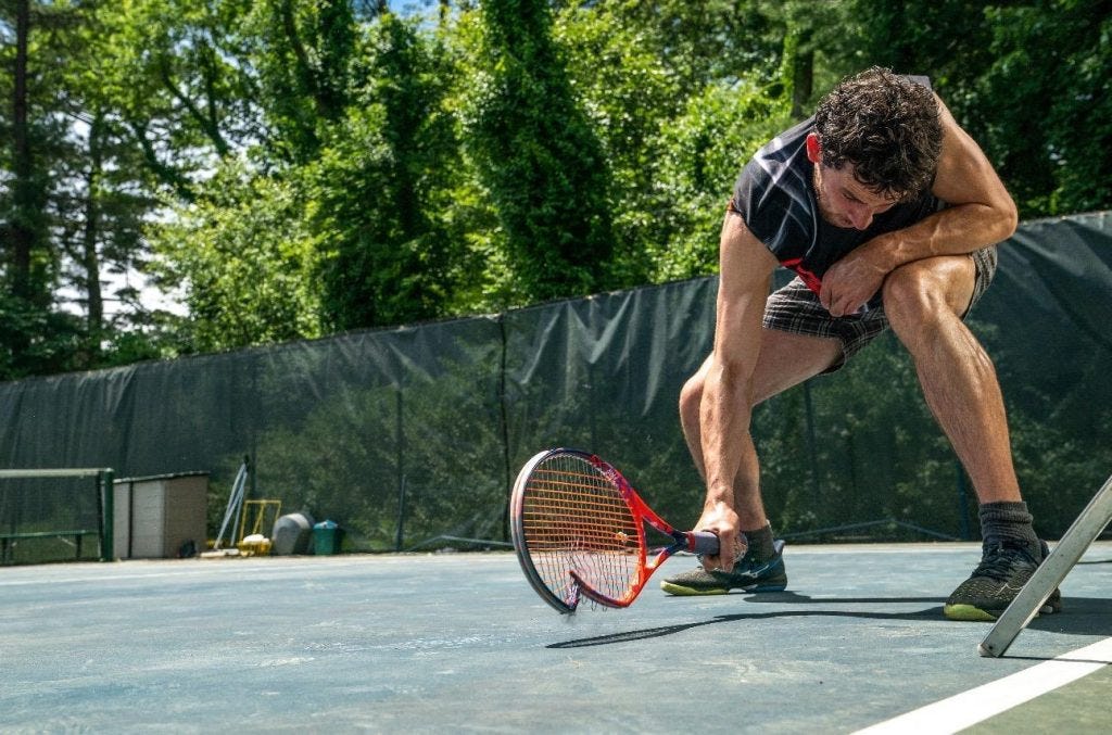 A sweaty Josh O'Connor smashing his racket against the ground